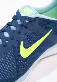 Scarpa da allenamento Nike con tomaia in mesh di colore blu scuro, dettagli testurizzati, logo Swoosh verde neon e lacci piatti blu.