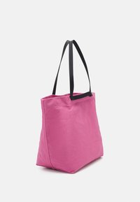 Różowa torba na ramię z płótna o strukturalnym kształcie, z dwoma czarnymi materiałowymi uchwytami i gładką teksturą. Prosty design, bez widocznych wzorów.