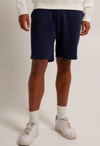 Navyblå shorts i bomullsblandning med elastisk midja, sidofickor och standardpassform. Matchas med vita sneakers och ribbade strumpor.