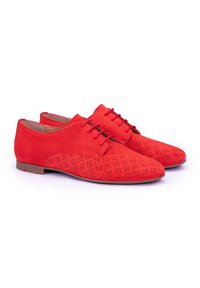 Zapatos de ante rojo con un patrón perforado en los laterales, suelas planas y un diseño clásico que incluye cordones en la parte superior.