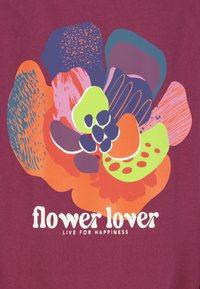 Bordeaux stof met een kleurrijk bloemenpatroon met vormen in oranje, groen, paars en roze. De tekst eronder leest "bloemenliefhebber" in het wit.