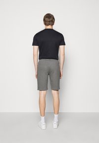 Černé tričko a šedé šortky z měkké tkaniny. Šortky mají střední délku a elastický pas. Bílé tenisky doladí celý vzhled.