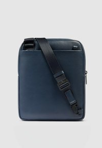 Borsa a tracolla in pelle blu navy con superficie testurizzata, tracolla regolabile e componenti neri. Forma rettangolare e design minimalista.