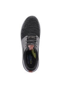 Zapatilla negra y gris con un upper de malla texturizada, cordones grises y un acento marrón en el talón. Cuenta con una plantilla acolchada y una puntera redondeada.