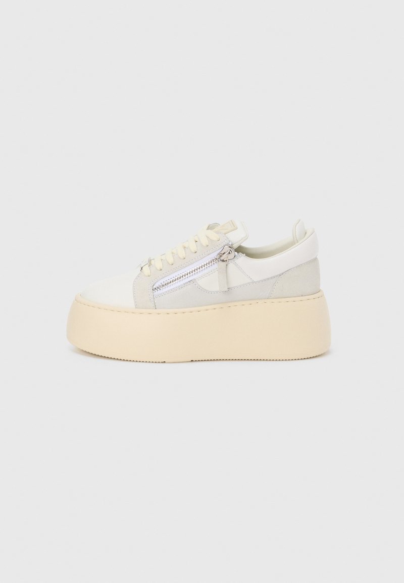 Schoenen met een laag platform in beige en off-white met veters aan de voorkant en een ritssluiting aan de zijkant, zijaanzicht op een effen achtergrond.