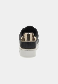 Schwarze Sneakers mit strukturiertem Obermaterial, geprägten Details und einem glänzenden goldenen Akzent an der Ferse. Weiße Gummisohle mit sichtbaren Nähten.