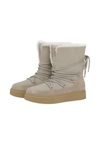 Beige nubuck enkelaars met een zachte nepbontvoering, vetersluiting aan de voorkant, gouden hardware accenten en een chunky beige zool.