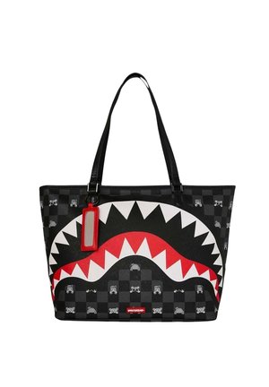 Bolsa tote negra con patrón de cuadros, diseño de boca de tiburón en rojo, blanco y negro, y una etiqueta rectangular roja colgando de una asa.