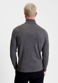 Maglione grigio a maniche lunghe con colletto alto, polsini e orlo a coste, realizzato in un morbido materiale lavorato a maglia, visto da dietro.