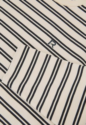 Cămașă cu mâneci lungi în dungi crem cu dungi bleumarin, având un guler nervurat și o literă "R" brodată în bleumarin pe piept.