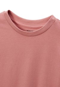 T-shirt en coton couleur rose poussiéreux, avec un col rond et une texture lisse. L'étiquette indique "MONODR". Design simple et épuré sans motifs ni accents.