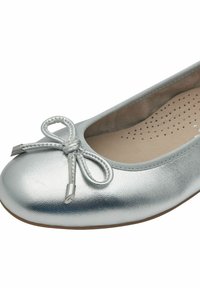 Ballerina in argento metallico con punta tonda, dettaglio di fiocco decorativo e texture sottile. L'interno presenta un'imbottitura perforata.