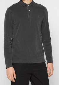 Pánská polo košile s dlouhými rukávy v tmavě šedé barvě z bavlny, s knoflíkovým límcem, jemným vyšitým logem a volným střihem s hladkým povrchem.