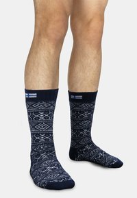 Marineblaue Socken mit einem geometrischen weißen Muster, ausgestattet mit einem gerippten Bündchen und verstärkter Spitze, gefertigt aus einem langlebigen, weichen Material.