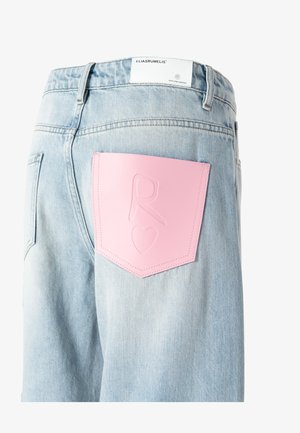 Lichtblauwe denim jeans met een roze geperst leren label op de achterzak, met de initialen "R" en een hartvorm.