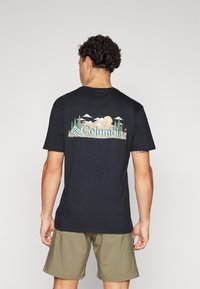 Tricou din bumbac negru, cu un grafic colorat ce reprezintă munți, copaci și soare, având textul "Columbia" în centru, scris cu albastru.