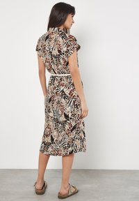 Abito midi con motivo floreale in beige e nero, con maniche corte, vita cintrata e tessuto morbido. Presenta una cintura e una gonna fluida.