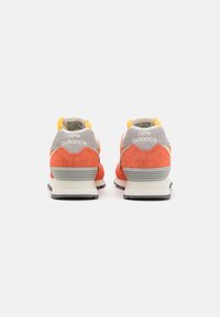 Orange and grey New Balance sneakers with suede and mesh materials; features a yellow heel tab and textured white midsole.