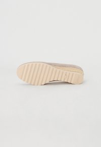 Beige shoe sole with textured rubber grip, featuring a ribbed pattern and subtle branding. Lightweight design, curved edges.