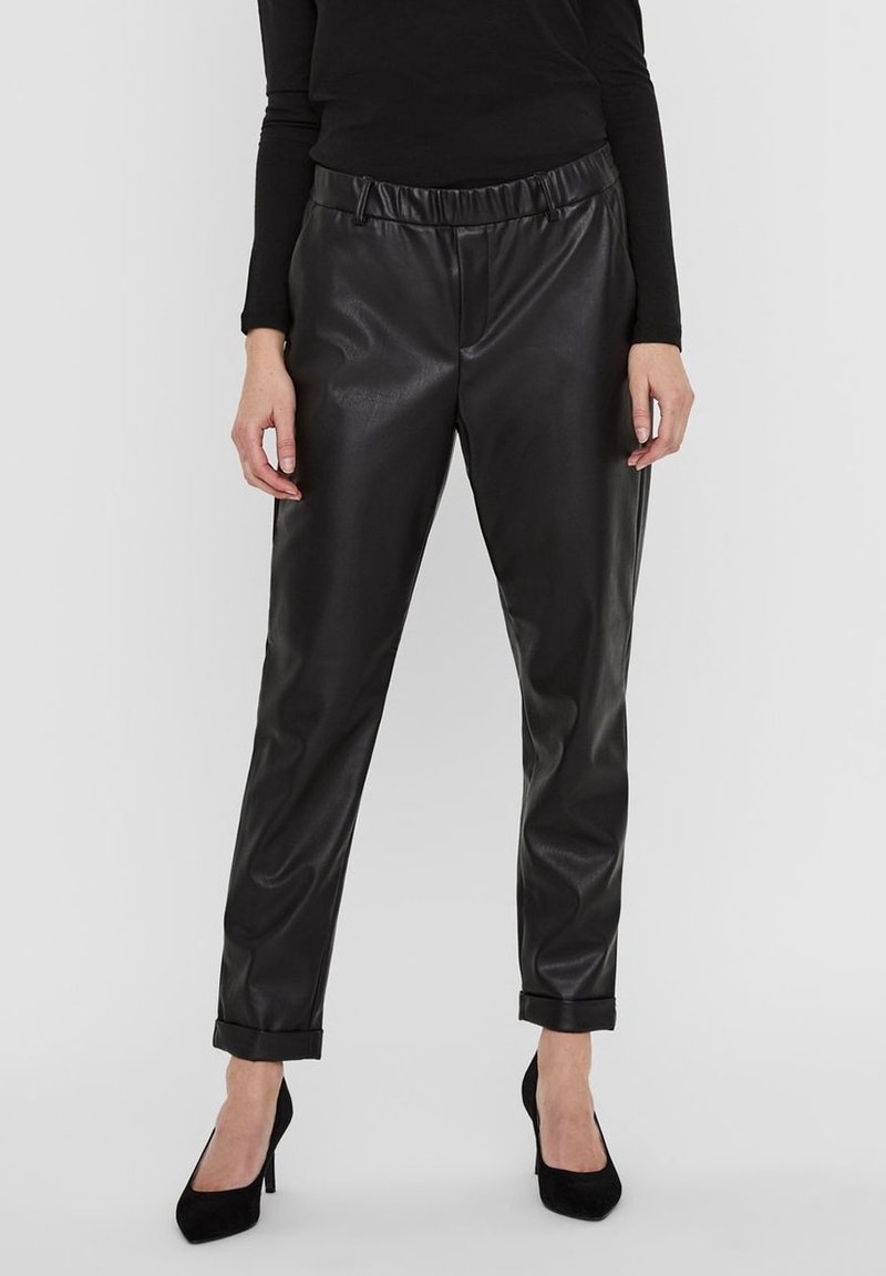Black faux leather trousers with a relaxed fit, elastic waistband, rolled cuffs, and a smooth, shiny texture. Paired with black heels.