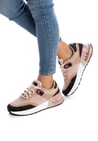 Baskets légères en mesh rose avec des accents noirs et un design à pois. Comprend un col rembourré, un système de laçage et un amorti à air visible.