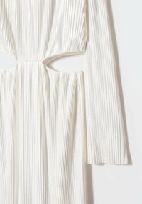 Robe blanche plissée à manches longues, présentant un détail découpé à la taille. Fabriquée en tissu texturé avec un léger éclat.