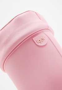 Bota de goma rosa con una textura suave, forma redonda y parte superior plegable. Presenta una etiqueta con el logo "igor" en el lateral.