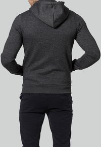 Mörkgrå hoodie med en känguruficka, åtsittande muddar och huva med dragsko. Mjuk bomullsblandning med en texturerad yta.