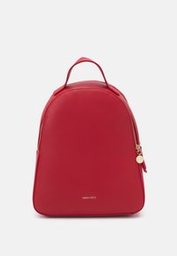 Sac à dos synthétique rouge au design arrondi, avec une fermeture éclair dorée et un logo en détail à la base. Dispose d'une poignée supérieure pour un transport facile.