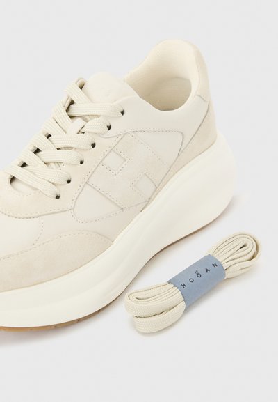 Εκρού αθλητικό παπούτσι με παχιά σόλα, πάνελ από σουέντ και δέρμα, με το εμπορικό σήμα "H" στο πλάι, συνοδευόμενο από αντίστοιχα ανταλλακτικά κορδόνια με λωρίδα με το εμπορικό σήμα.