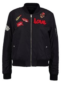 Czarna kurtka bomberka na zamek błyskawiczny, z prążkowanymi mankietami i licznymi kolorowymi naszywkami, w tym ustami, szminką oraz napisem "love".