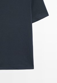 T-shirt bleu marine à manches courtes présenté de la taille aux manches avec une couture propre le long de l'ourlet sur fond blanc.