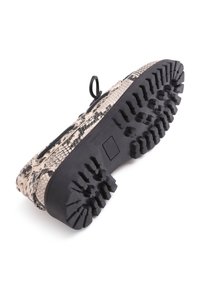 Black rubber sole with raised treads, upper in beige and black snake-patterned material. Features a pull tab at the heel.