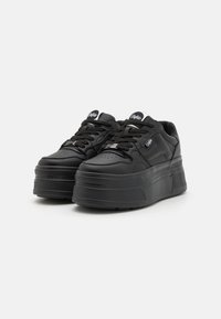 Black platform sneakers with a smooth leather finish, round toe, and textured rubber sole. Features lace-up design and subtle branding on tongue.
