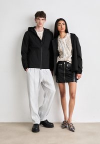 Jachete negre cu fermoar, cămăși cu motive, pantaloni albi plisati și o fustă din piele cu fermoare; pantofii modelului sunt masivi și cu curele.