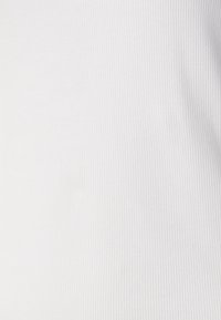 Vit ribbad tyg med vertikala linjer, slät textur och inga synliga mönster eller utsmyckningar. Lämplig för olika klädesapplikationer.