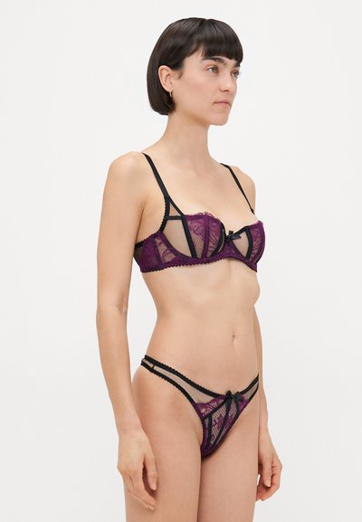Purple lace bralette and matching thong with black accents, featuring sheer panels, scalloped edges, and front bow detail.