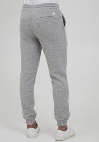 Gray, textured jogger pants with an elastic waistband, side pockets, and a patch pocket on the back. Elastic cuffs at the ankles.
