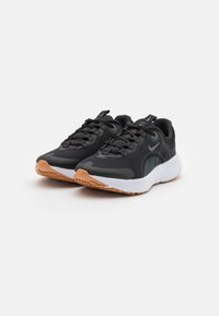 Zapatillas deportivas negras con parte superior de malla, suela de goma texturizada y acentos reflectantes. Media suela blanca de contraste con suela de goma.