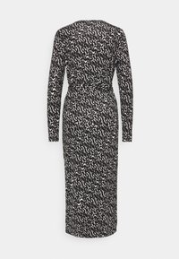 Robe midi à manches longues à motifs noir et blanc avec taille cintrée et tissu en maille douce, vue de dos.