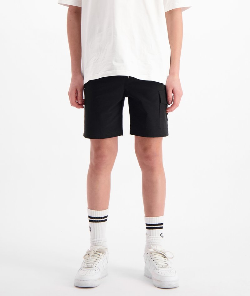 Zwarte shorts met een ritssluiting en zijvakjes, gedragen met witte sneakers en gestreepte crew-sokken, en een losse witte t-shirt.