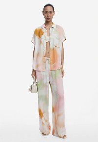 Lightweight, short-sleeve shirt and wide-leg pants in pastel floral print. Fabric is soft with flowy texture. Includes drawstring detailing.