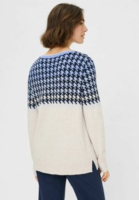 Strickpullover mit einem Hahnentrittmuster in Marineblau, Hellblau und Creme; gerippter Saum; leicht lockere Passform; seitliche Schlitze.