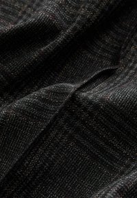Strukturierten schwarzen Stoff mit einem gewebten Muster, das subtile, multicolore Fäden aufweist. Die Oberfläche hat eine weiche, leicht erhabene Textur.