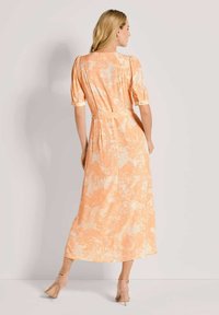 Maxikleid aus weichem orangefarbenem Stoff mit floralem Muster, kurzen Puffärmeln und einem Bindegürtel in der Taille, mit einer lässigen Silhouette.