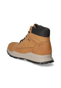 Bota de cuero marrón con cuello de tela negra, superficie texturizada, parte delantera con cordones y suela de goma negra robusta. Marca visible en el lado.