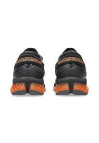 Czarne buty sportowe z teksturowanym materiałem, z pomarańczowym akcentem oraz wyraźnym wsparciem pięty, zaprojektowane z myślą o komforcie i stabilności.