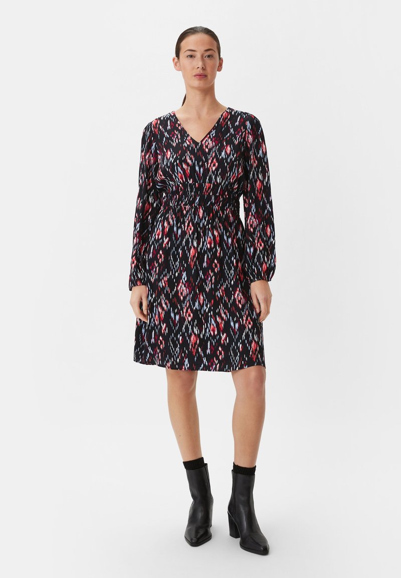Schwarzes Kleid mit V-Ausschnitt, langen Ärmeln und elastischem Bund. Es hat ein buntes geometrisches Muster in Rot, Blau und Weiß.