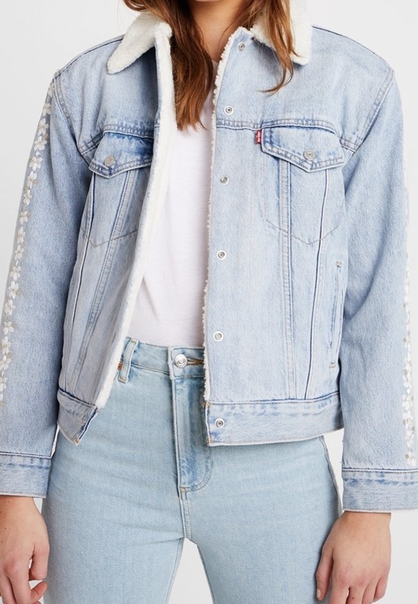 Jasnoniebieska dżinsowa kurtka z pokazowym kołnierzem z futra, dwoma kieszeniami na piersi oraz kwiatowym haftem wzdłuż rękawów. Zapinana na guziki, o skróconym kroju.