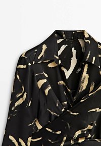 Schwarze Satinbluse mit Wickeldesign, versehen mit abstrakten goldenen und cremigen Pinselstrichmustern; klassischer Kragen und Knopfverschluss.